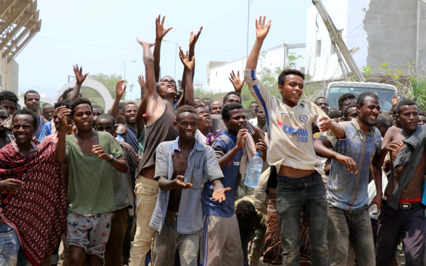 Des migrants africains reçoivent de la nourriture et de l’eau dans un stade de football à Aden au Yémen, où les autorités les ont confinés (AFP)