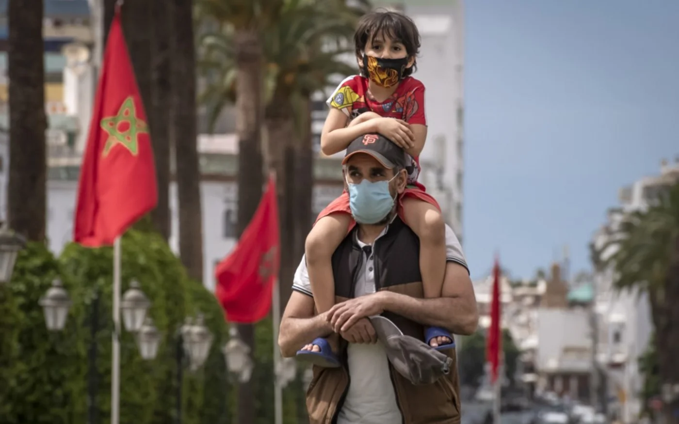 Un père porte son fils sur son épaule alors qu’ils marchent dans le centre de Rabat, la capitale du Maroc, le 16 juin 2020 (AFP)