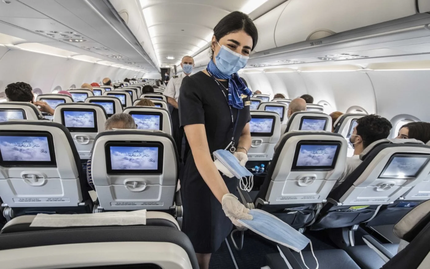 Le personnel de cabine égyptien distribue des masques sur un vol intérieur à l’aéroport international du Caire le 18 juin 2020 (AFP)
