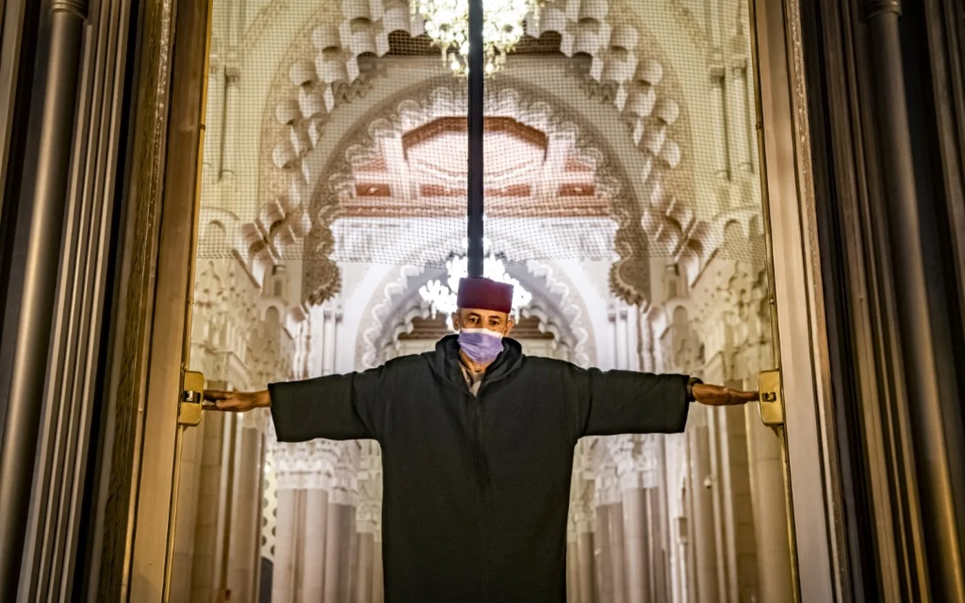 Un travailleur masqué ouvre les portes de la mosquée Hassan II, l’une des plus grandes du continent africain, à Casablanca au Maroc le 16 juin 2020 (AFP)