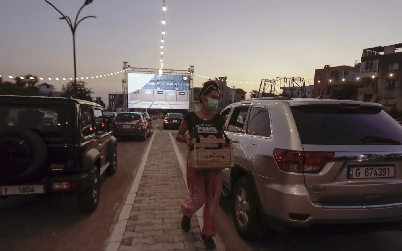 Une Libanaise vend des collations et des boissons à des jeunes qui attendent dans un cinéma drive-in à Byblos, au nord de Beyrouth, le 18 juillet 2020 (AFP)