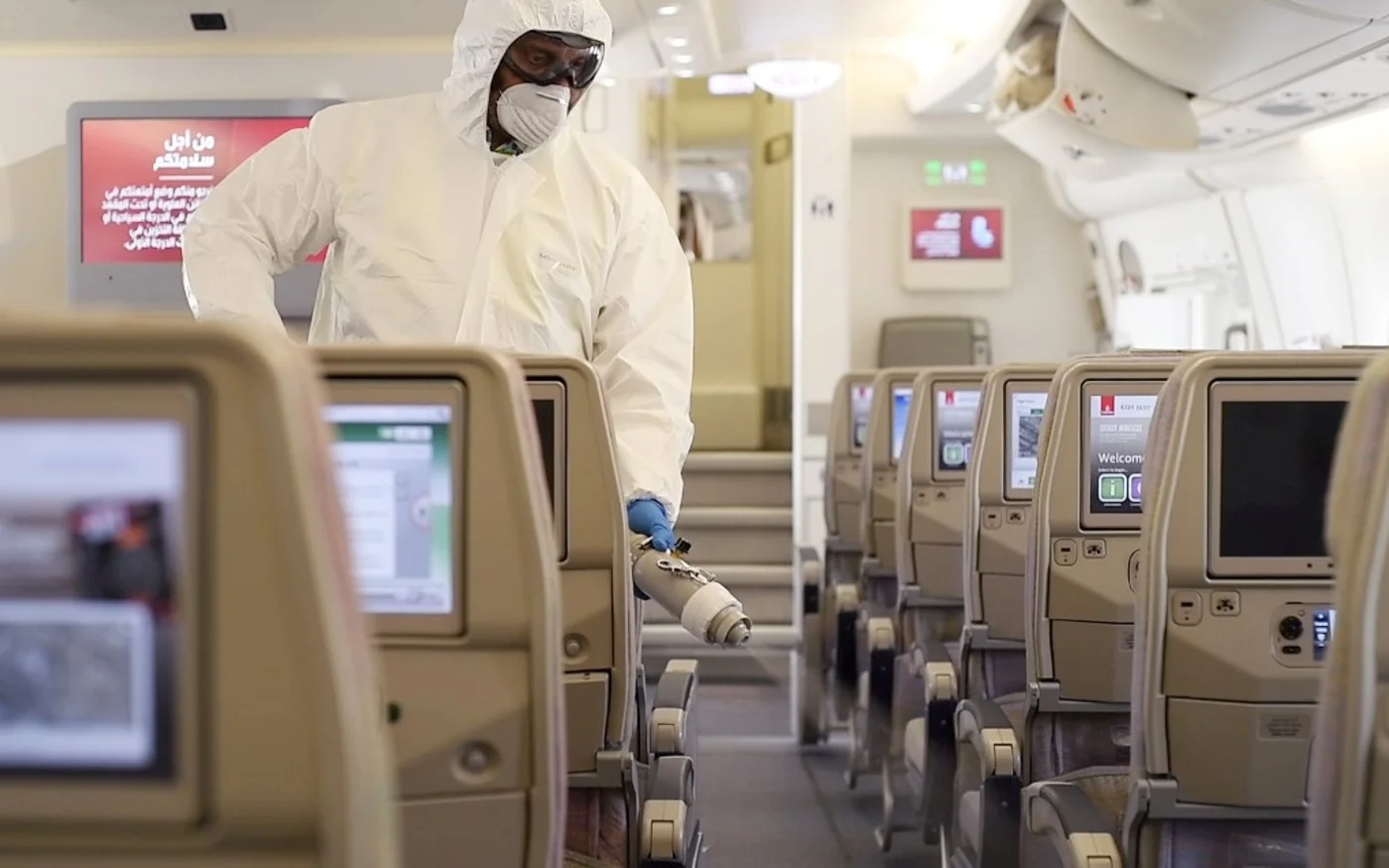 Un membre du personnel de nettoyage pulvérisant du désinfectant à bord d’un avion Emirates Airbus (AFP)