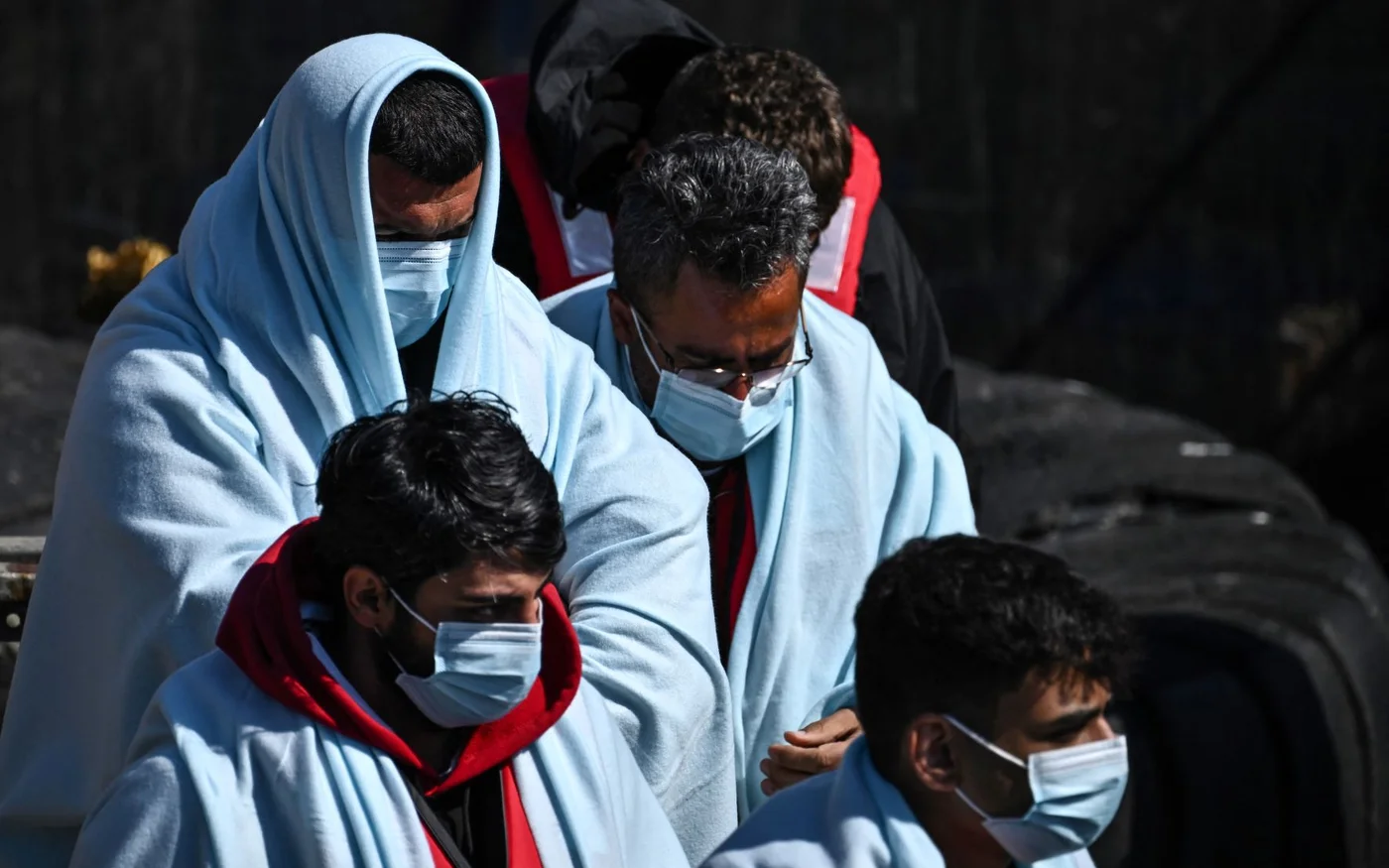 Des migrants débarquent d’un canot pneumatique des garde-frontières britanniques, après avoir tenté de traverser la Manche, en juin&nbsp;2022 (AFP)