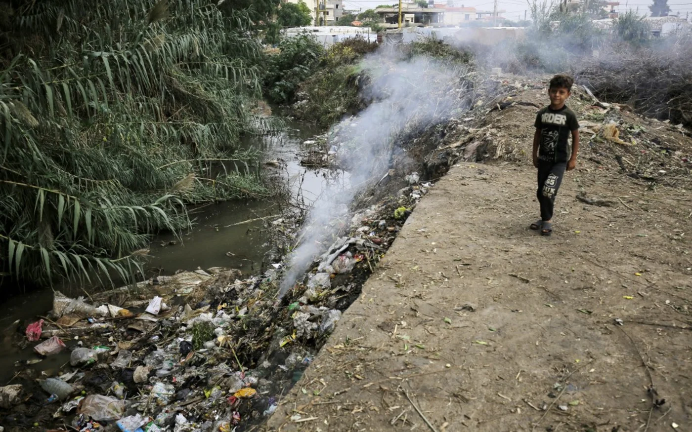 Un enfant se tient à côté d’un tas d’ordures dans un camp de fortune pour réfugiés syriens à Talhayat, dans le district d’Akkar, au nord du Liban, le 26 octobre 2022 (AFP/ Ibrahim Chalhoub)