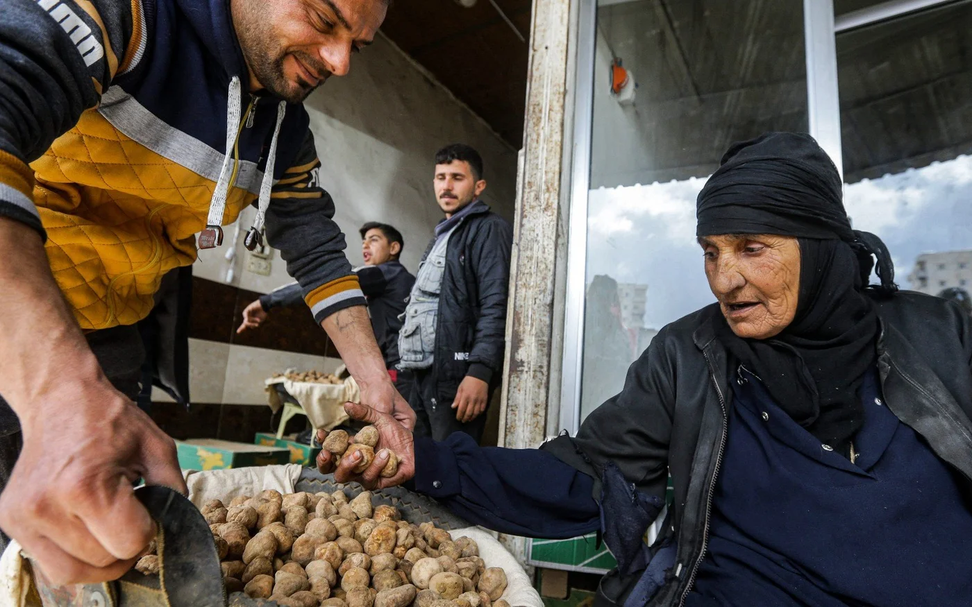 Un commerçant aide une femme à trier des truffes du désert sur un marché de la ville de Hama, dans le centre-ouest de la Syrie, le 6&nbsp;mars (AFP)
