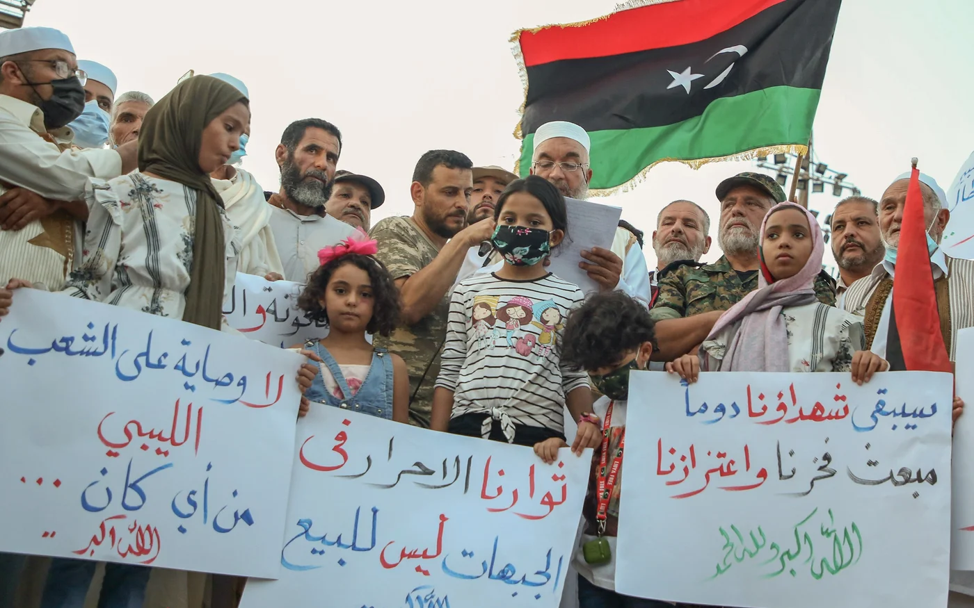Des manifestants libyens brandissent des pancartes et des drapeaux libyens lors d’un rassemblement sur la place des Martyrs de Tripoli pour protester contre la détérioration de la situation politique et sécuritaire et des conditions de vie, le 2&nbsp;octobre (AFP)