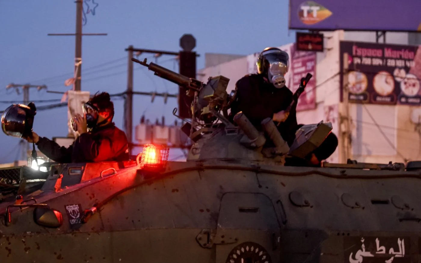 Des membres de la Garde nationale tunisienne assis sur leur blindé, à Ettadhamen, le 17 janvier 2021 (AFP)