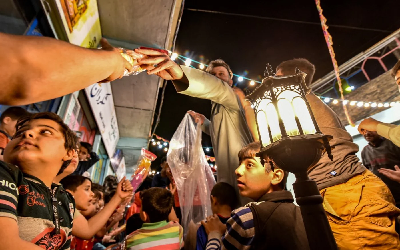 Des volontaires distribuent de jouets aux enfants pendant la première nuit du Ramadan, le 13 avril 2021, à Mossoul (AFP)