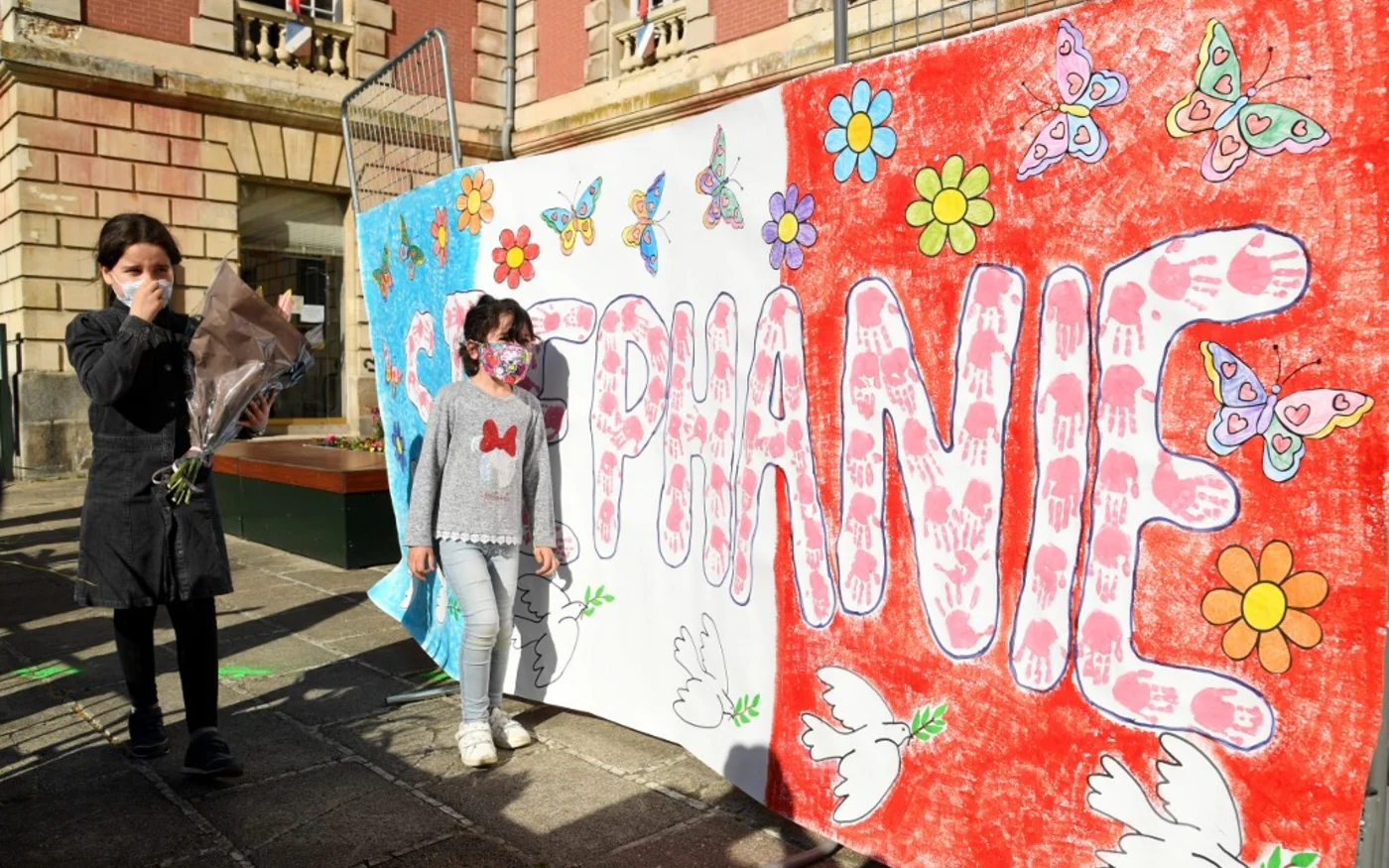 Des enfants apportent des fleurs lors d’un rassemblement en hommage à la policière tuée le 26 avril 2021 à Rambouillet (AFP/Bertrand Guay)