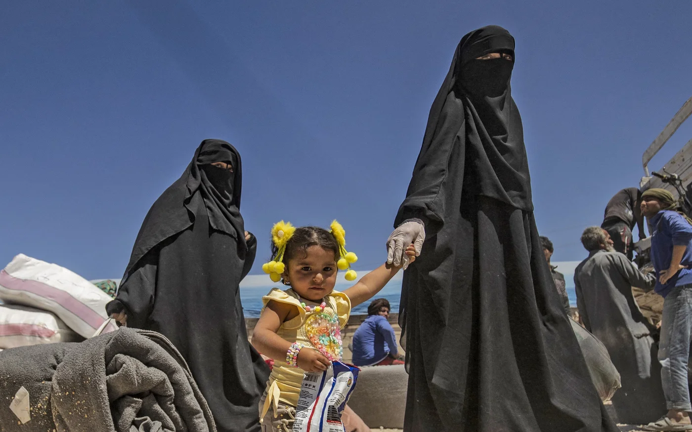Des femmes marchent avec des enfants et des effets personnels lors de la libération d’un groupe de familles syriennes du camp d’al-Hol administré par les Kurdes, le 11&nbsp;mai&nbsp;2021 (AFP)