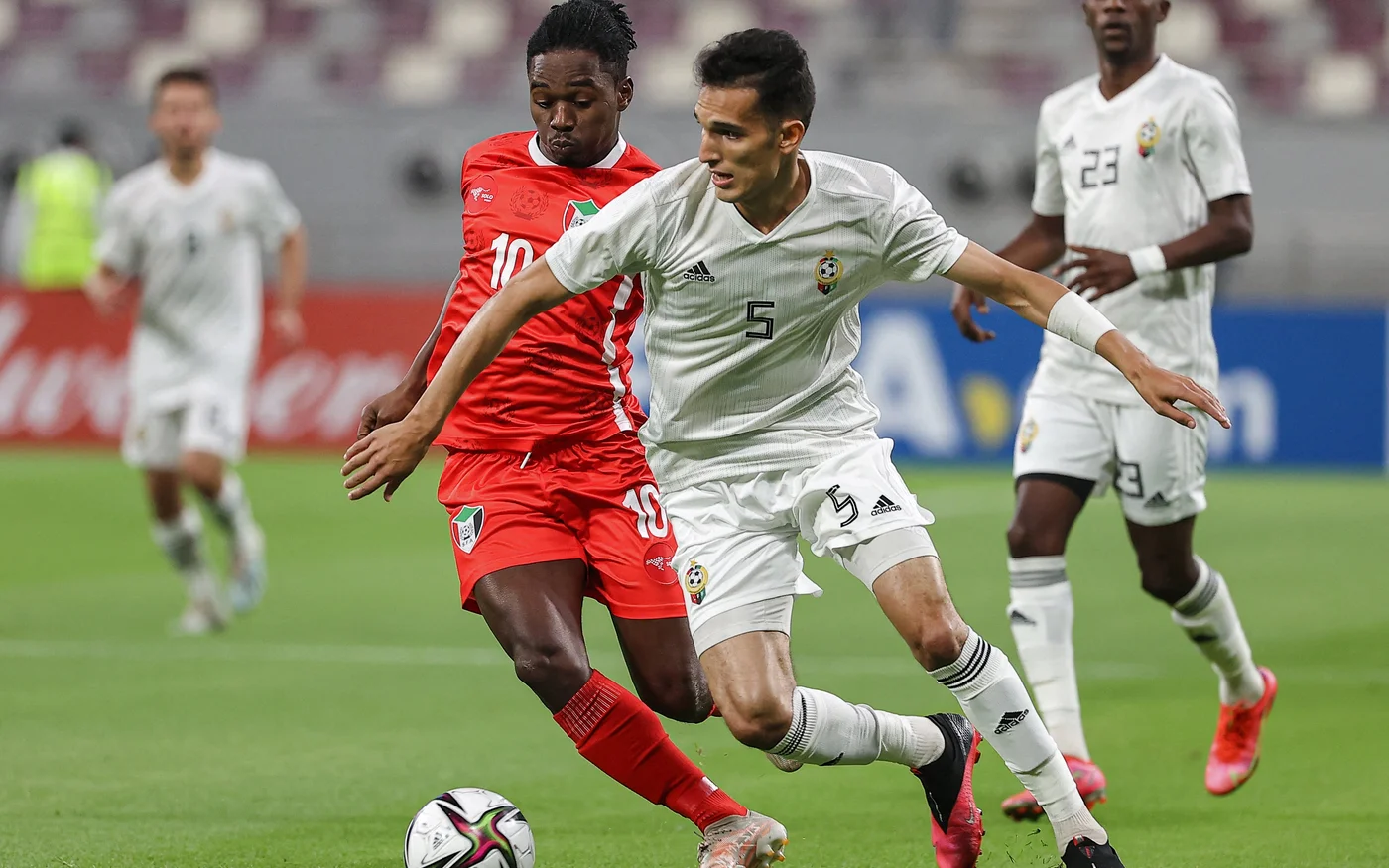 L’attaquant soudanais Mohamed Abdelrahman (en rouge) lors d’un match de barrages de la Coupe arabe de la FIFA 2021 contre la Libye (AFP)