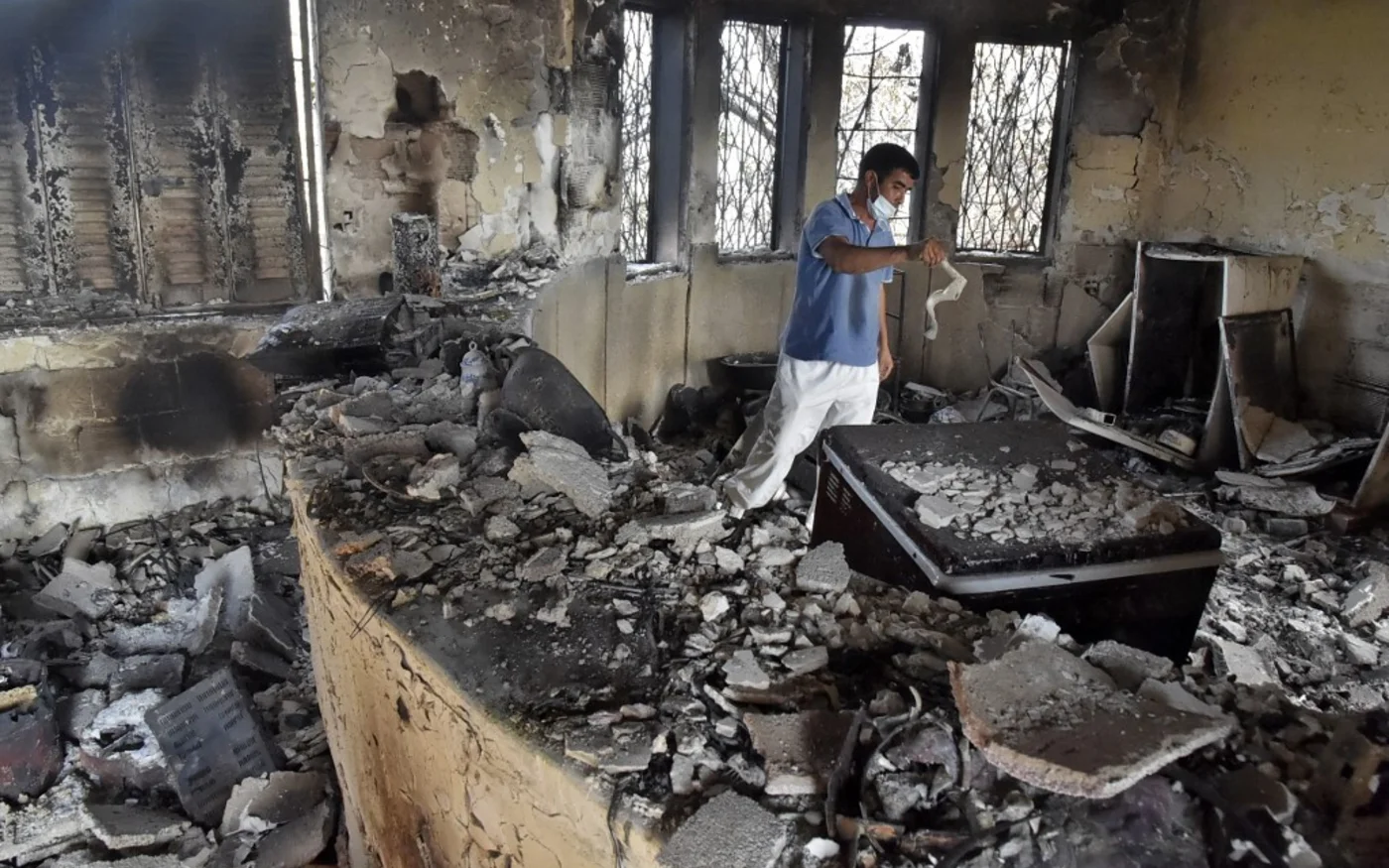 Un habitants du village d’Aït Daoud inspecte sa maison après le sinistre, le 13 août 2021 (AFP/Ryad Kramdi)
