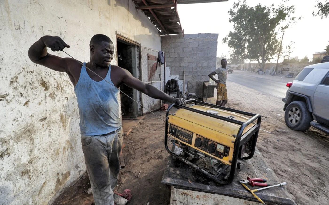 Un technicien répare un générateur à l’extérieur d’une boutique de la capitale de la Libye, Tripoli, le 26 août 2021 (AFP/Mahmud Turkia) 