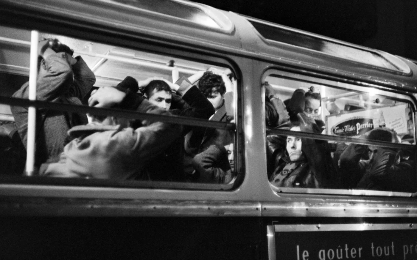 Manifestants algériens arrêtés pendant la manifestation du 17 octobre 1961, dans un bus de la police, les mains sur la tête (AFP)