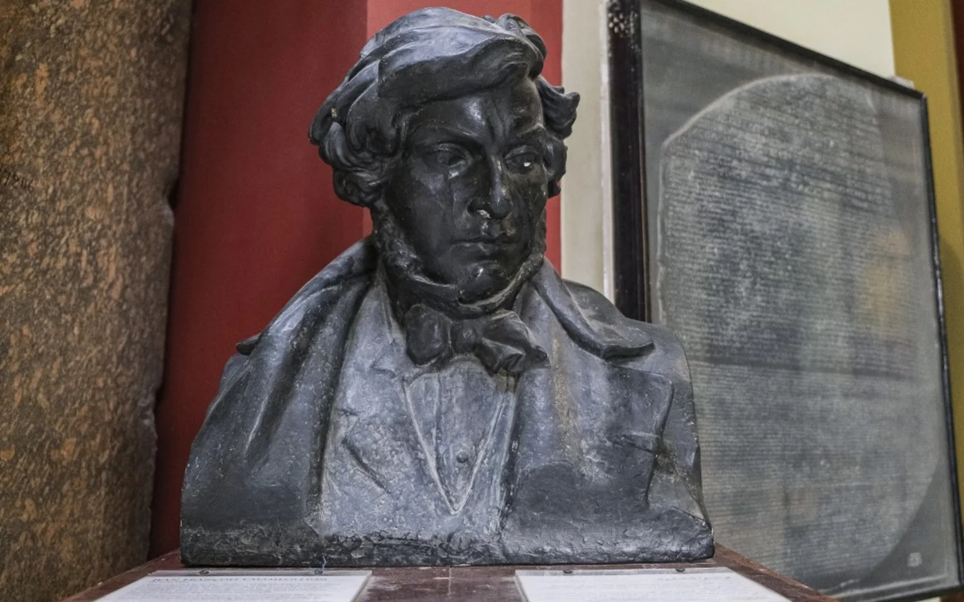 Derrière une réplique de la pierre de Rosette, le buste du savant et philologue français Jean-François Champollion, connu pour son déchiffrement de l’écriture hiéroglyphique égyptienne, à l’entrée du Musée égyptien du Caire (AFP/Amir Makar)