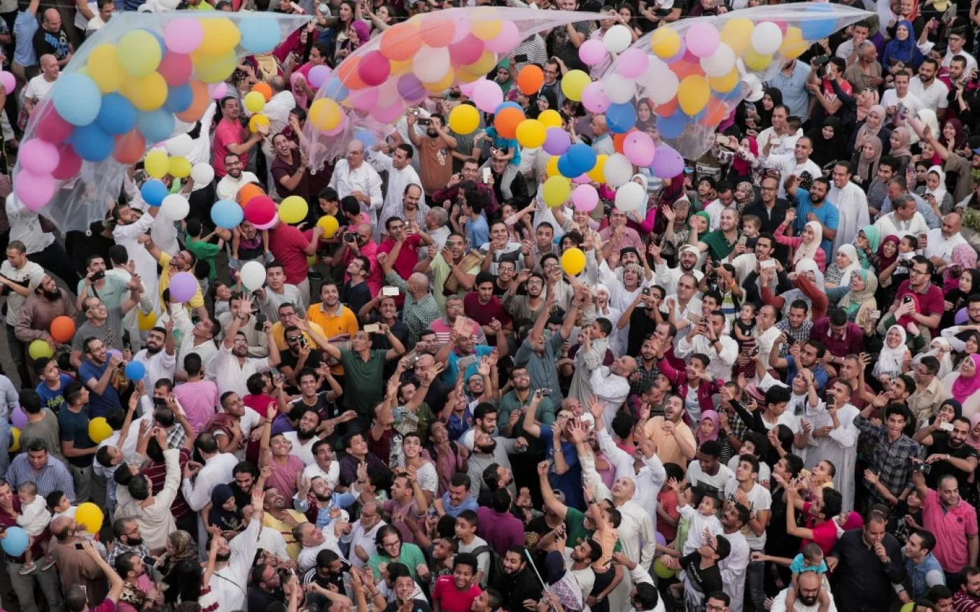 Des adultes et des enfants jouent avec des ballons après les prières matinales de l’Aïd, au Caire (AFP)