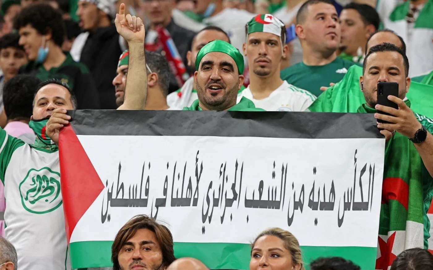 Des supporters algériens brandissent le drapeau palestinien comportant le message «&nbsp;le trophée est un cadeau du peuple algérien pour notre famille en Palestine&nbsp;» lors de la finale de la Coupe arabe de la FIFA, le 18&nbsp;décembre&nbsp;2021 (AFP)