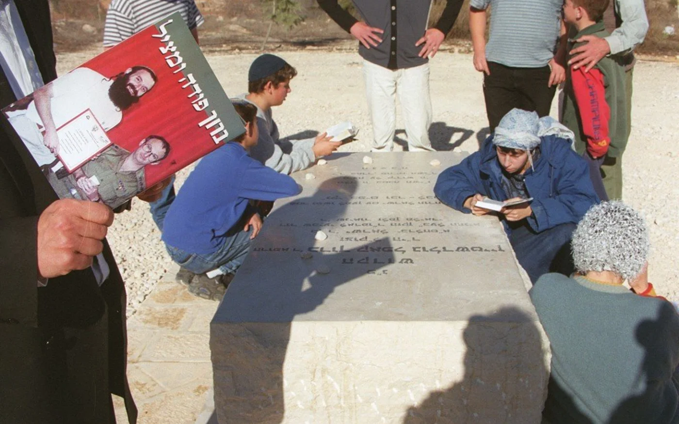 Un colon israélien lit un livre intitulé «&nbsp;Baruch le sauveur&nbsp;» sur la tombe de l’extrémiste Baruch Goldstein dans la colonie illégale de Kiriyat Arba, en Cisjordanie occupée, le 29&nbsp;décembre&nbsp;1999 (AFP)