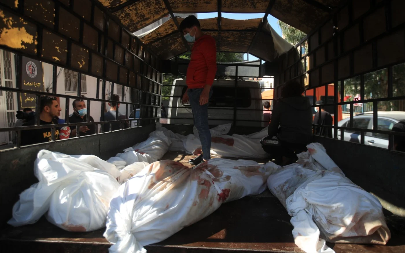 Un homme se tient près des corps, à l’arrière d'un camion, à l’hôpital al-Ahli al-Arab (MEE/Muhammad Zanon)