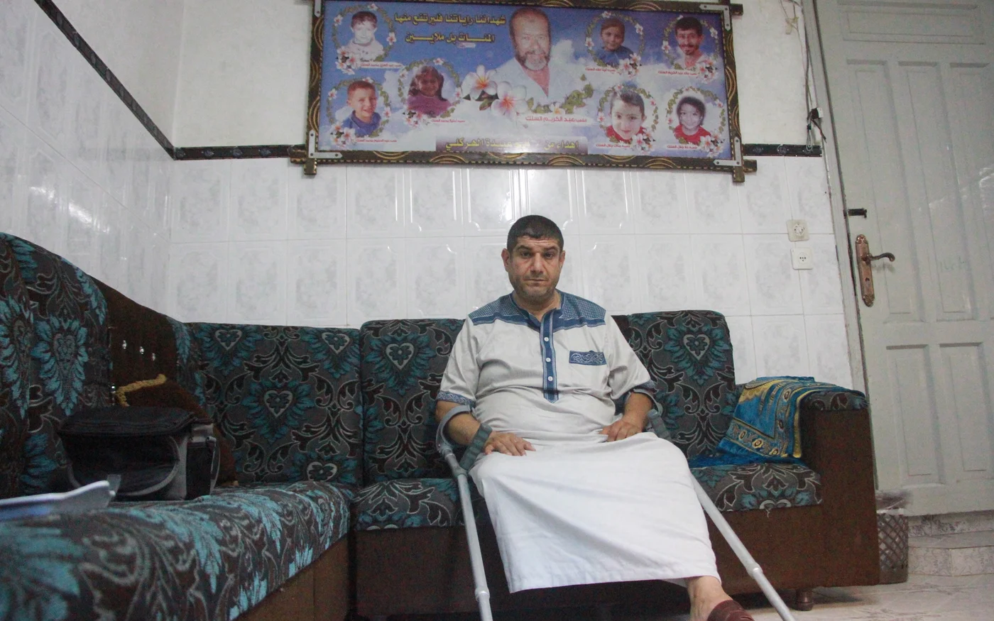 Mohammed al-Silk devant une photo de ses enfants, de son père et de ses neveux tués sur le toit de sa maison lors des frappes aériennes israéliennes de 2014 sur Gaza (MEE/Ahmed al-Sammak)