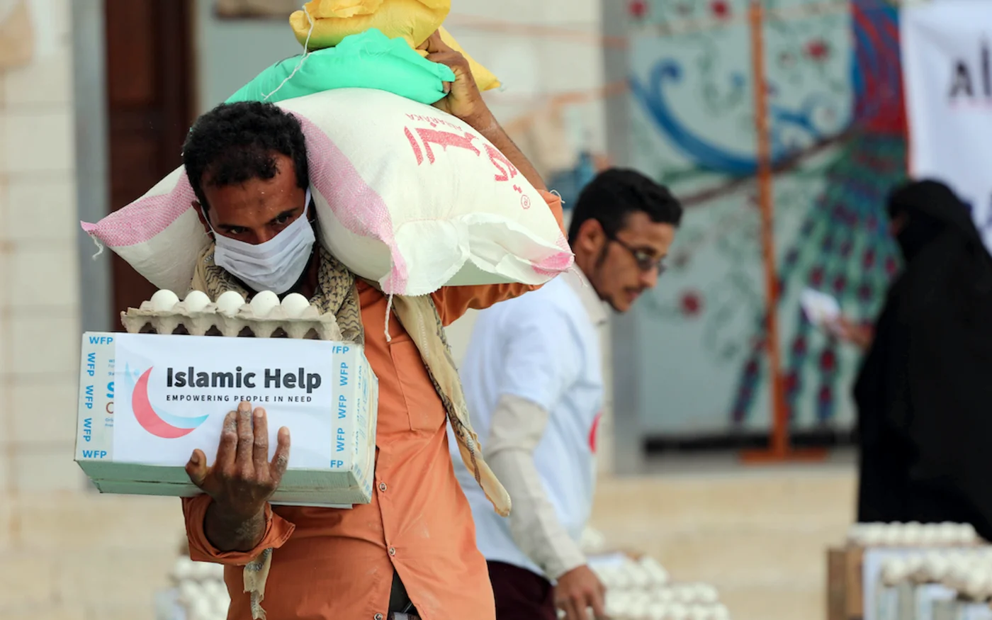 Un homme portant un masque récupère un colis alimentaire, à Taez, au Yémen, le 8 mai 2020 (AFP)