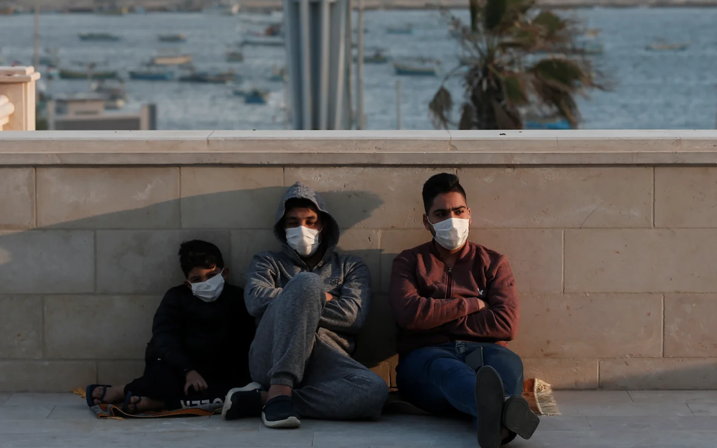Des jeunes palestiniens sont assis devant une mosquée, à Gaza, le 24 mai 2020 (AFP)