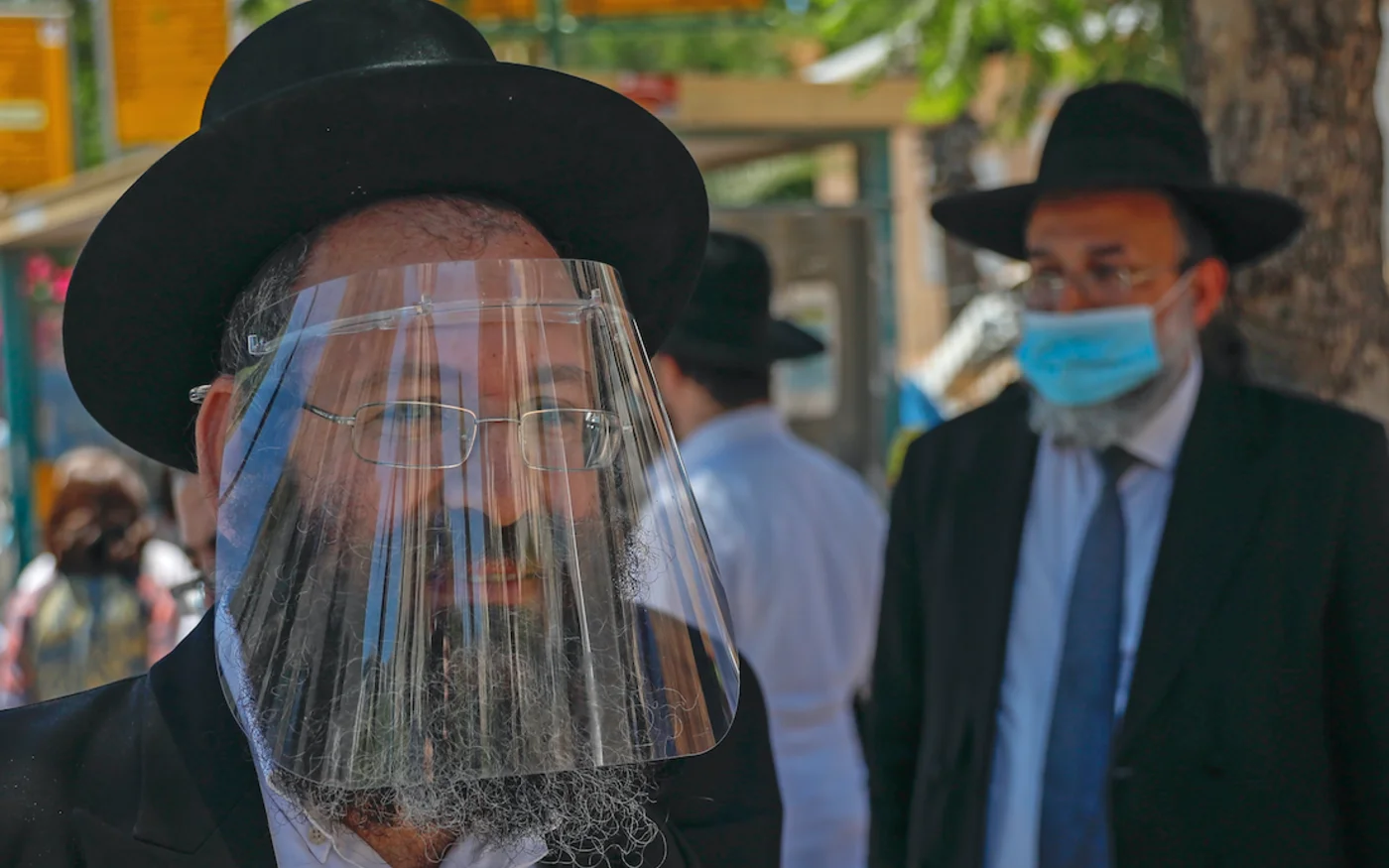 Un juif ultra-orthodoxe, portant un écran facial, traverse un poste de contrôle de police dans la ville d'Elad, au centre d'Israël, le 24 juin 2020 (AFP)