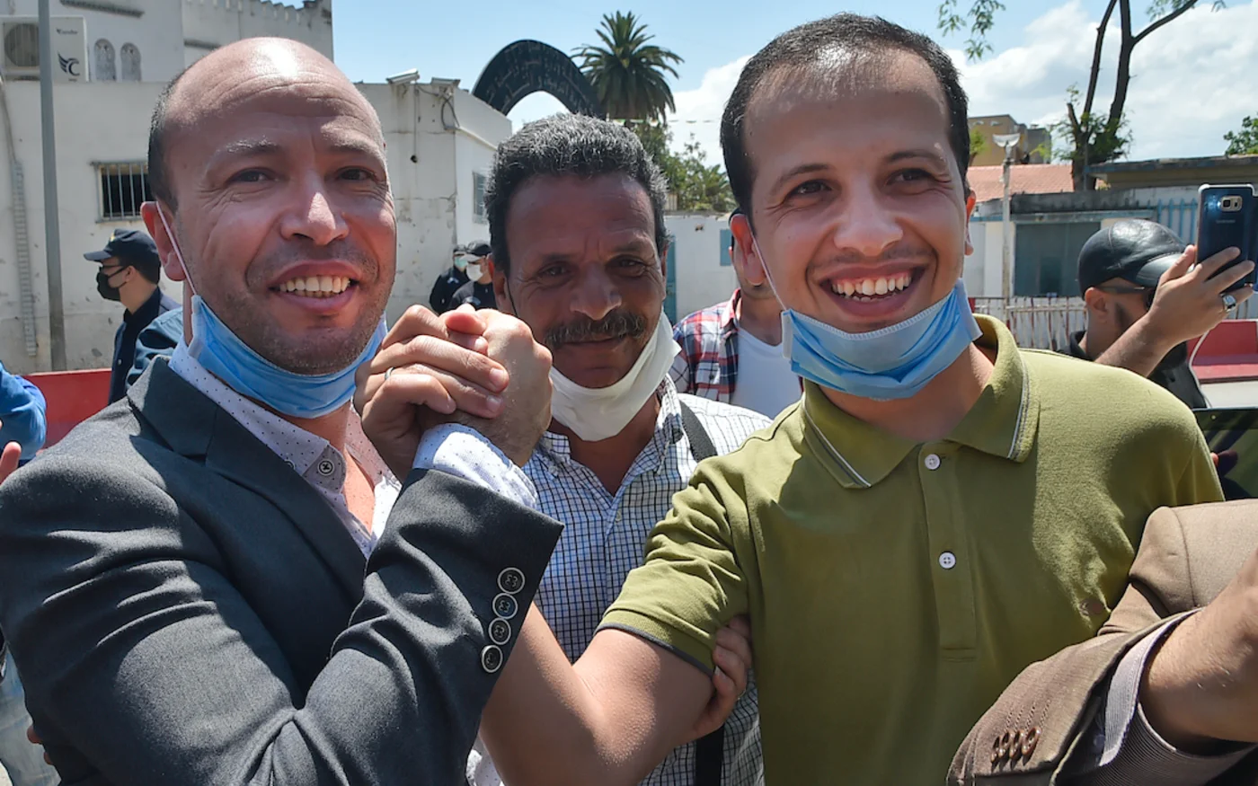 Abdelouahab Fersaoui (à gauche) et Ibrahim Daouadji (à droite) se tiennent la main lors de leur libération de la prison d'El Harrach, dans la capitale Alger, le 18 mai 2020 (AFP)