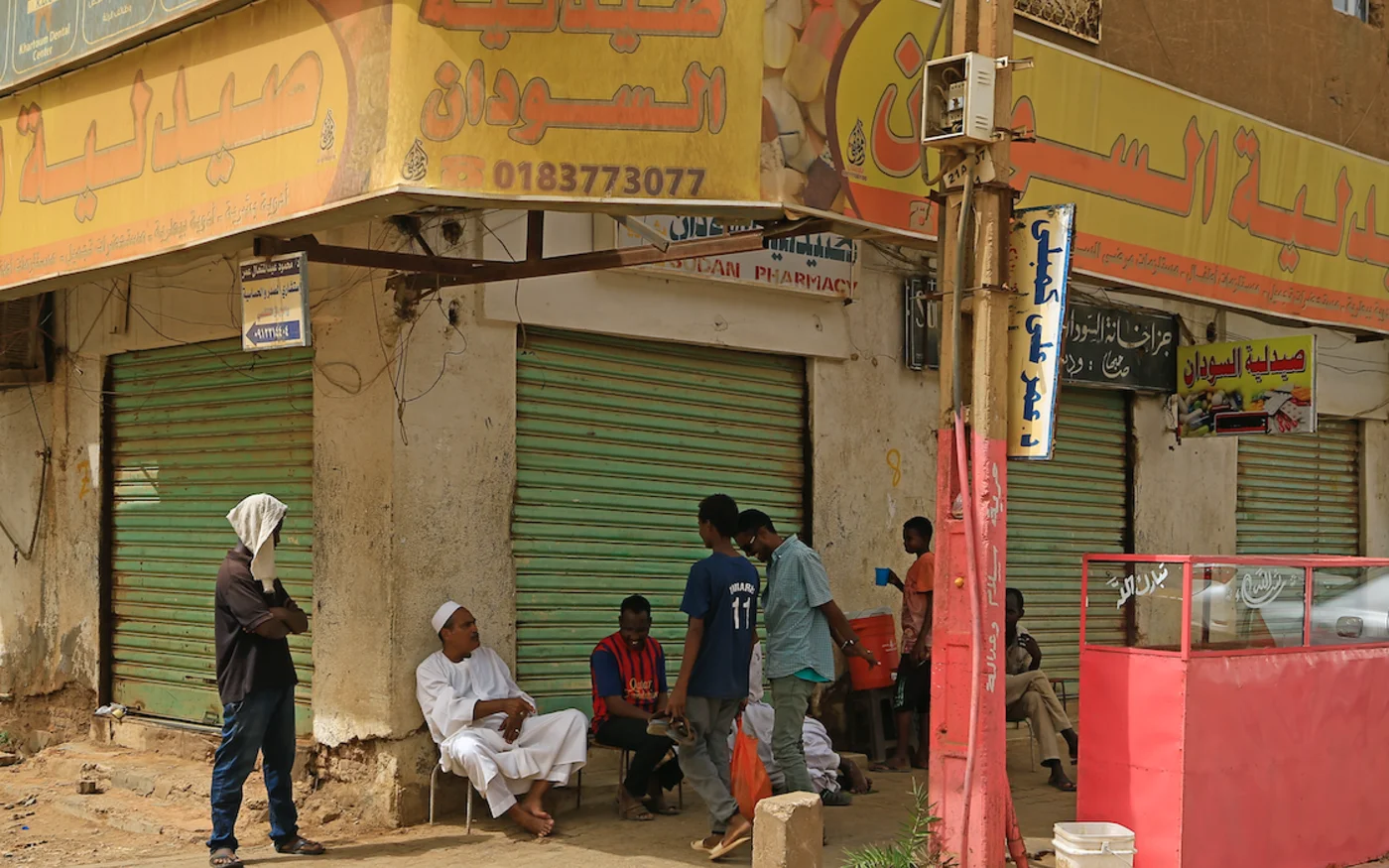Des jeunes soudanais sont assis devant des pharmacies fermées, à Khartoum, le 18 juin 2020 (AFP) 