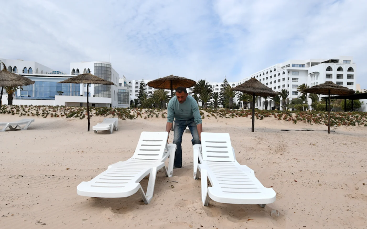 Un employé tunisien installe des chaises sur la plage d'un hôtel, à Sousse au sud de la capitale Tunis, le 21 avril 2017 (AFP)