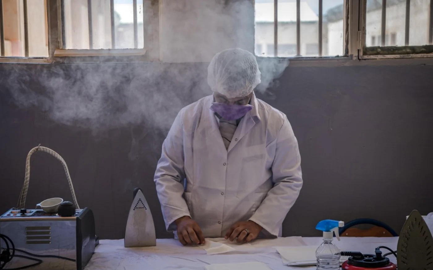 Un détenu repasse des masques de protection cousus par ses codétenus à la prison d'Oukacha à Casablanca, le 18 mai 2020 (AFP)