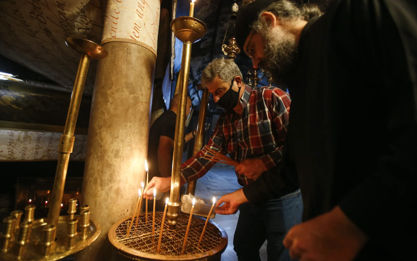 Des fidèles chrétiens allument des bougies dans l'église de la Nativité de Bethléem après sa réouverture, le 26 mai 2020 (AFP)