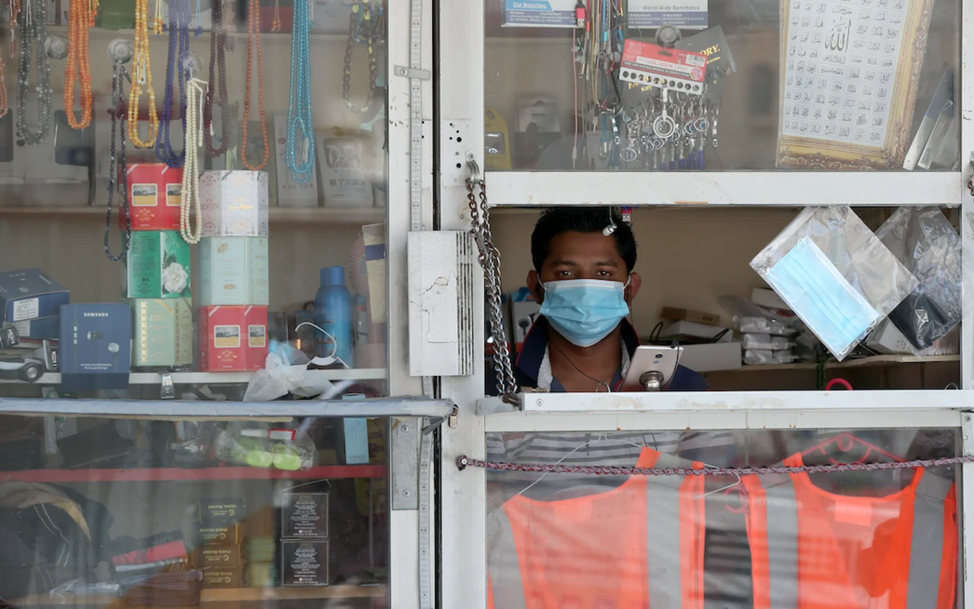 Un commerçant regarde par la fenêtre de son magasin, à Doha, le 17 mai 2020 (AFP)