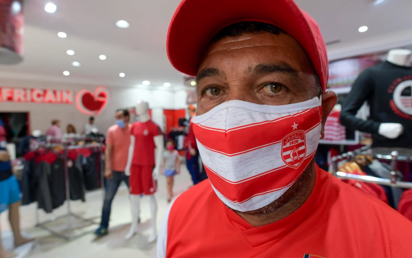 Un Tunisien porte un masque avec l'emblème et les couleurs du Club Africain de Tunisie, à Tunis, le 22 mai 2020 (AFP)