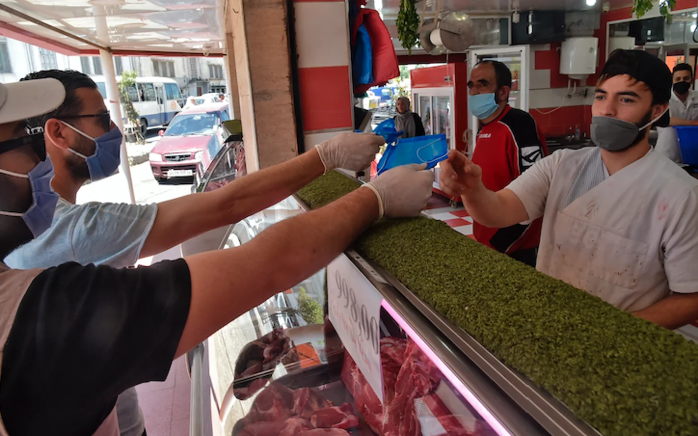 Un boucher reçoit un masque distribué par des bénévoles de la société civile, à Alger, le 21 mai 2020 (AFP)
