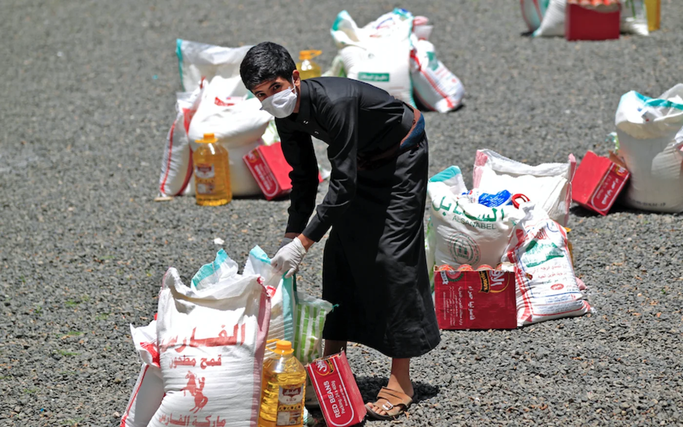 Un jeune yéménite récupère un colis alimentaire, à Sanaa, le 17 mai 2020 (AFP)