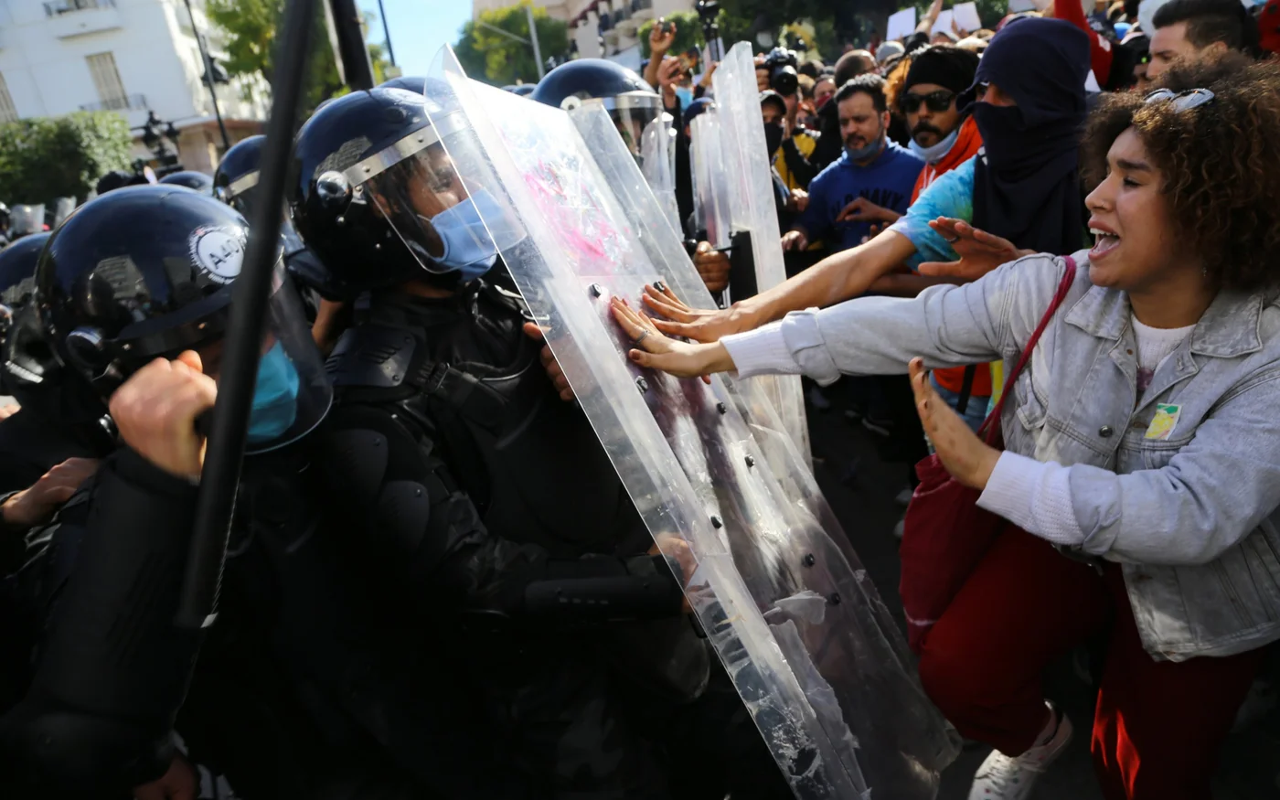 Des manifestants tunisiens affrontent la police qui forme un bouclier humain devant le ministère de l’Intérieur dans la capitale Tunis, le 30 janvier 2021 (AFP)