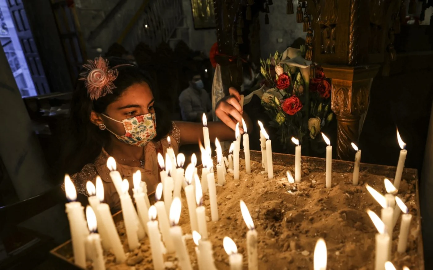 Une jeune Palestinienne orthodoxe grecque allume un cierge lors de la messe du matin de Pâque à l’église Saint-Porphyre de Gaza (AFP)