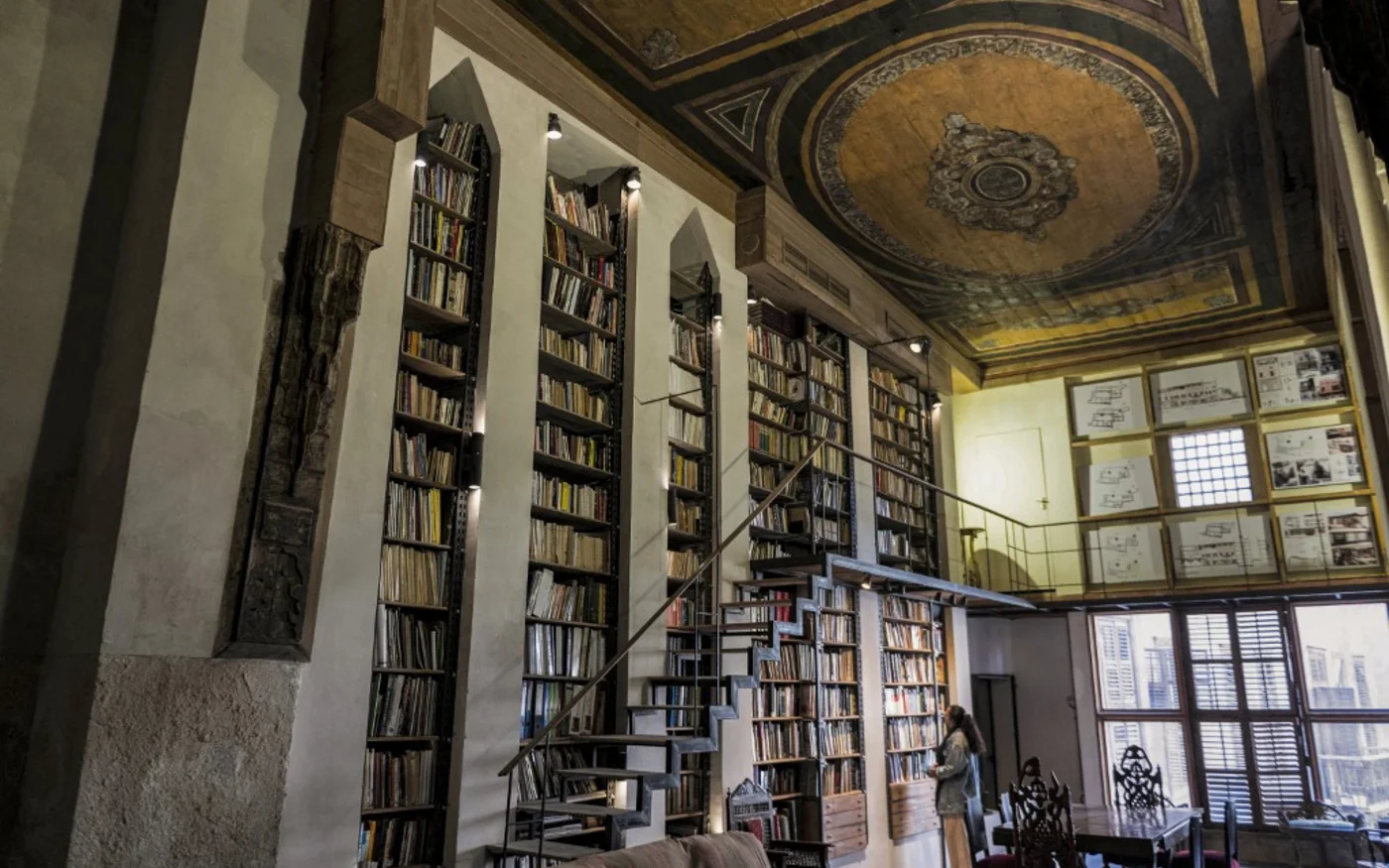 Une femme parcourt les étagères de la bibliothèque de la maison historique Beit Yakan, dans le quartier d'al-Darb al-Ahmar au Caire, le 6 décembre 2022 (AFP/Mohamed Hossam)