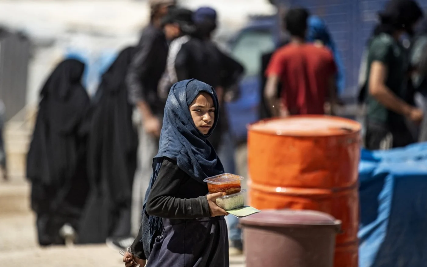 Une petite fille porte une ration de nourriture dans le camp syrien d’al-Hol, le 11 mai 2021 (AFP)