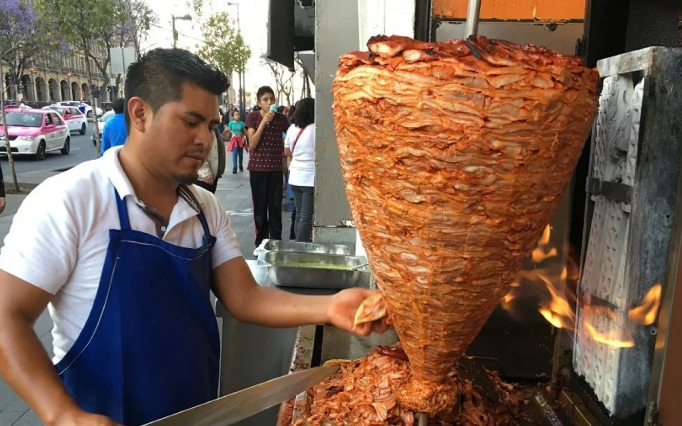 Un vendeur à Mexico découpe de la viande pour préparer des tacos al pastor, un plat probablement dérivé du chawarma, introduit par les immigrés libanais au début du XXe siècle (MEE/Alex Shams)