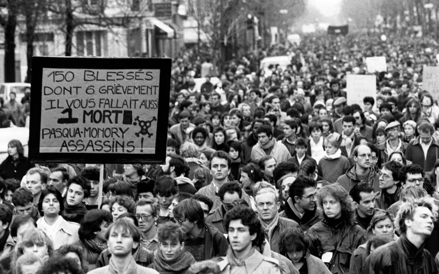Plusieurs milliers de personnes manifestent silencieusement à Paris, le 6 décembre 1986, de la place de la Sorbonne à l’hôpital Cochin où repose le corps de Malik Oussekine, le jeune étudiant décédé le matin même après avoir été violemment frappé par des policiers en marge d’une manifestation étudiante contre le projet de réforme universitaire du ministre Alain Devaquet (AFP/Michel Gange)
