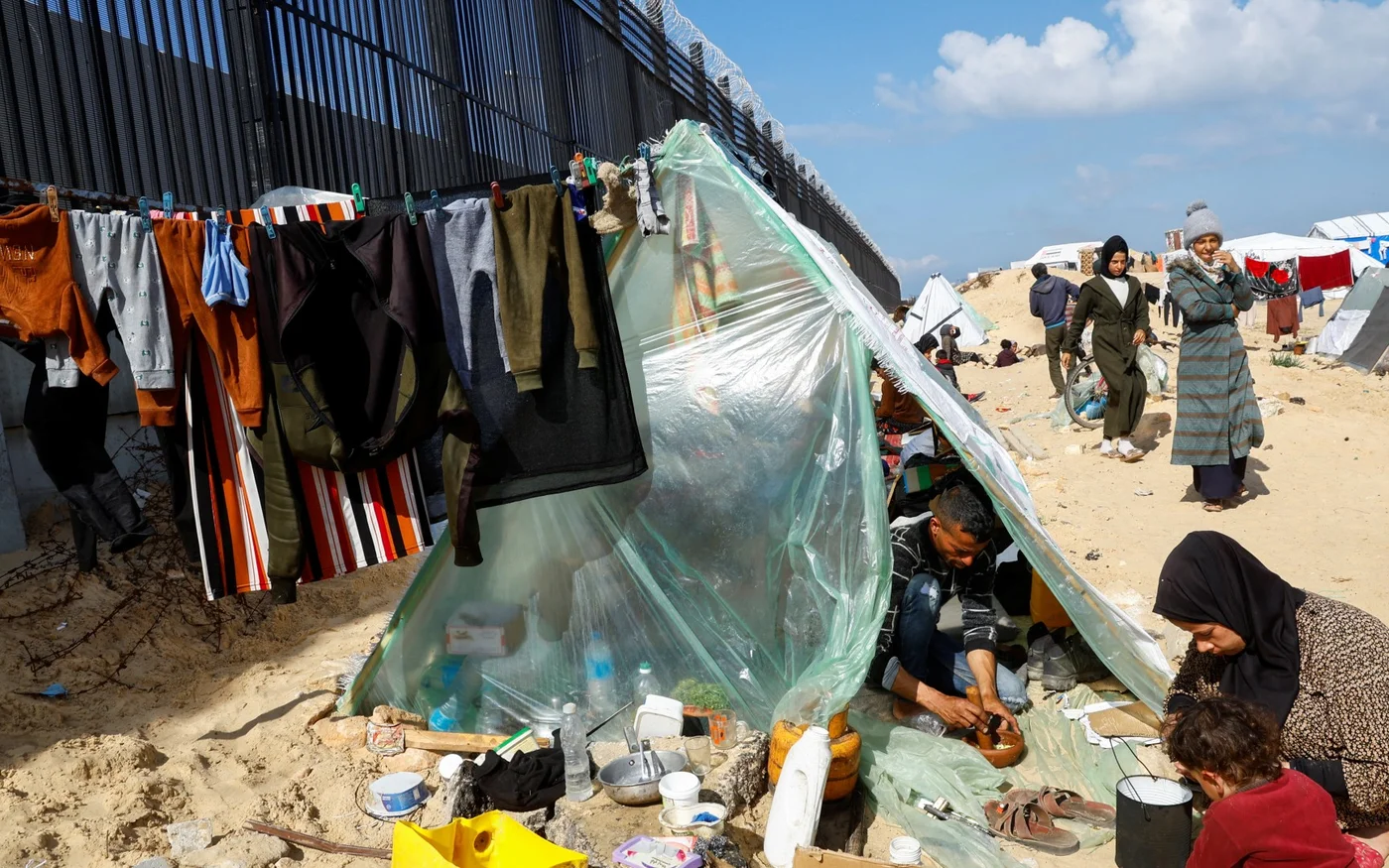 Une famille palestinienne déplacée qui a fui sa maison à la suite des frappes israéliennes prépare son repas dans leur abri à la frontière égyptienne, à Rafah, dans la bande de Gaza, le 10 février (Reuters/Mohammed Salem)