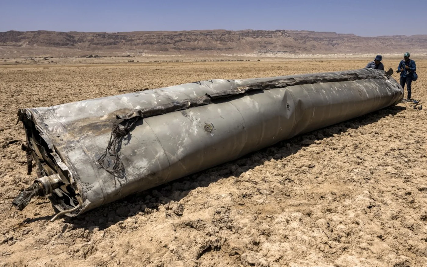 Des photographes près des restes d’un missile ayant atterri sur la rive de la mer Morte, une semaine après l’attaque de missiles par l’Iran le 13 avril, le 21 avril 2024 (Menahem Kahana/AFP)