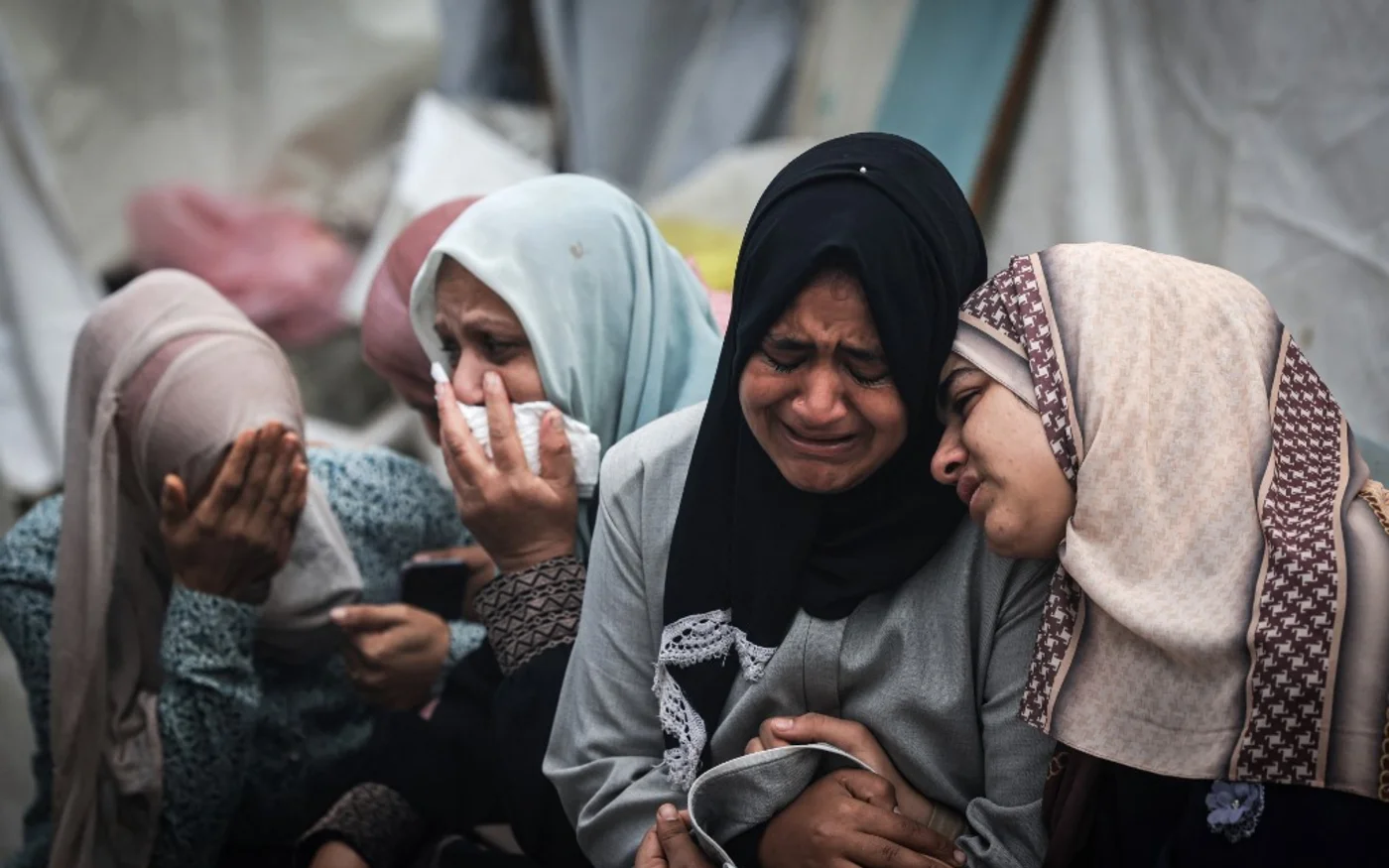 Des Palestiniens pleurent leurs proches, tués lors d’une frappe israélienne nocturne contre le camp de réfugiés d’al-Maghazi, lors de funérailles collectives à l’hôpital al-Aqsa de Deir al-Balah, dans le centre de la bande de Gaza, le 25 décembre 2023 (AFP/Mahmud Hams)