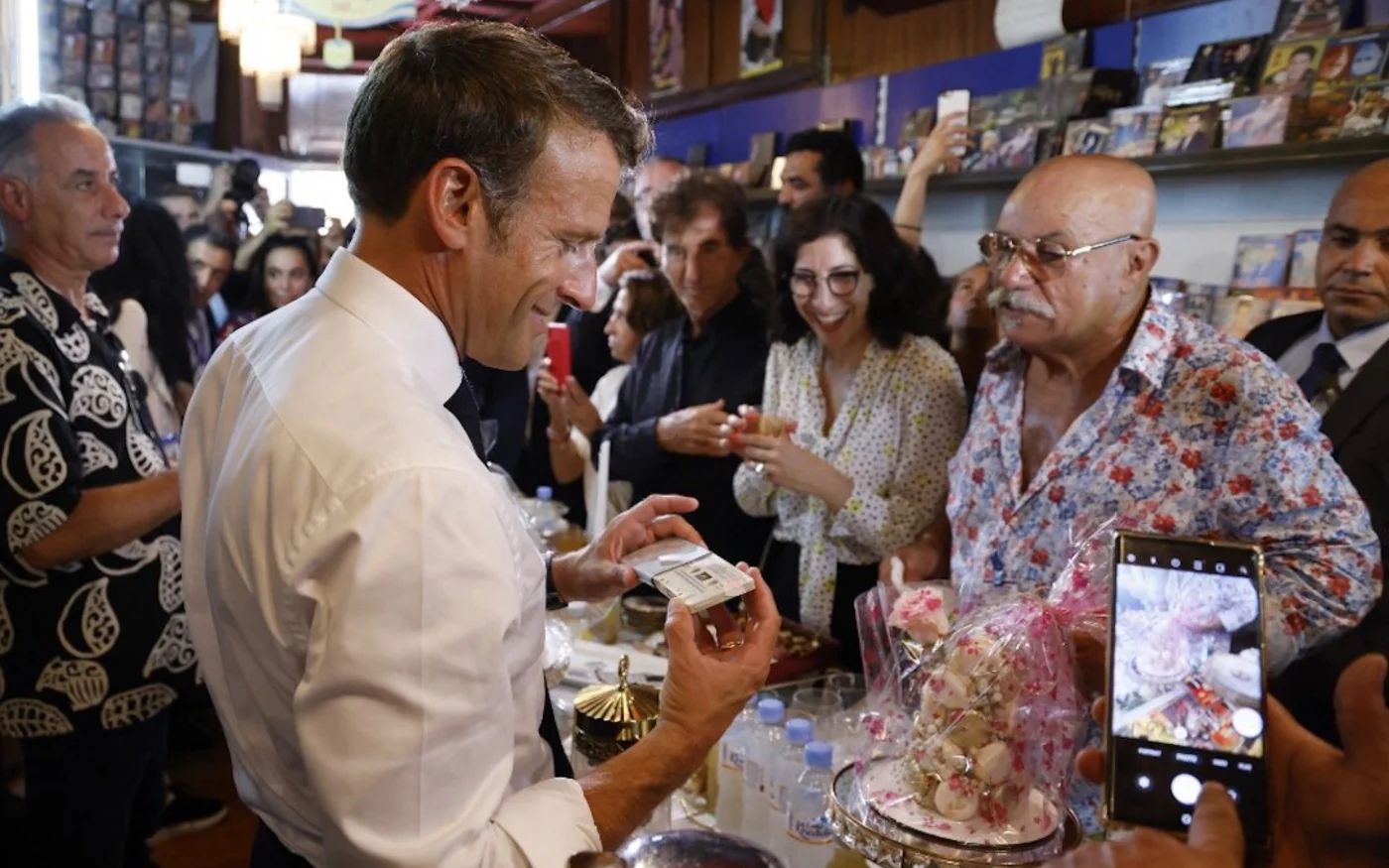Le président français Emmanuel Macron visite Disco Maghreb, le label mythique de la musique raï, devant son propriétaire, Boualem Benhaoua (à droite), à Oran le 27 août 2022 (AFP/Ludovic Marin)