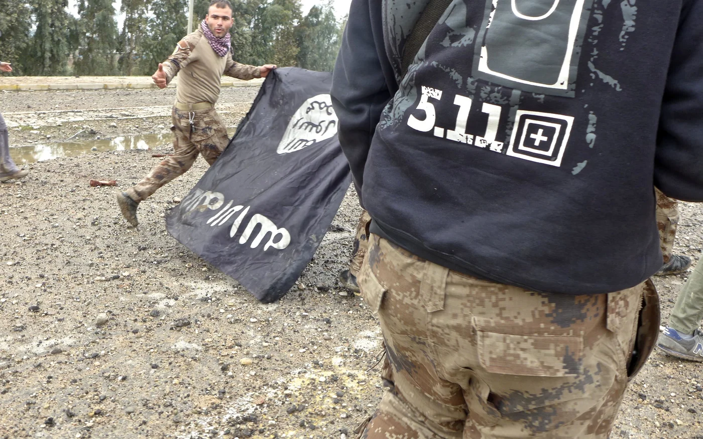 Des membres des forces spéciales irakiennes retirent un drapeau de l’EI à Mossoul en 2017 (MEE/Tom Westcott)