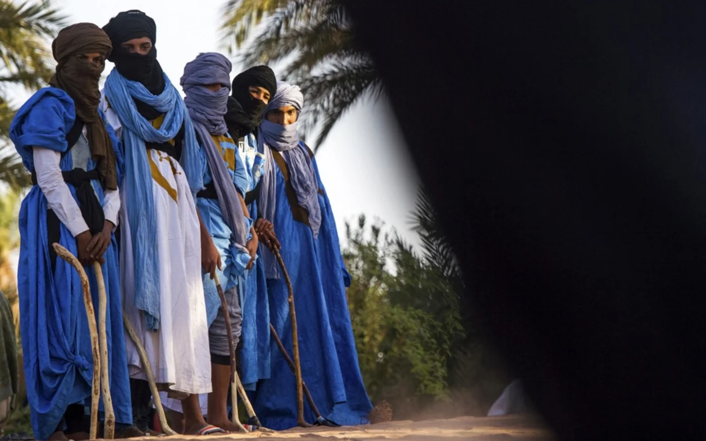 Des Marocains portant des vêtements traditionnels tiennent des bâtons de hockey utilisés pour jouer au hockey sur sable lors du 15e Festival international des nomades à M’hamid el-Ghizlane, dans le désert du Sahara, le 22 mars 2018 (AFP/Fadel Senna)