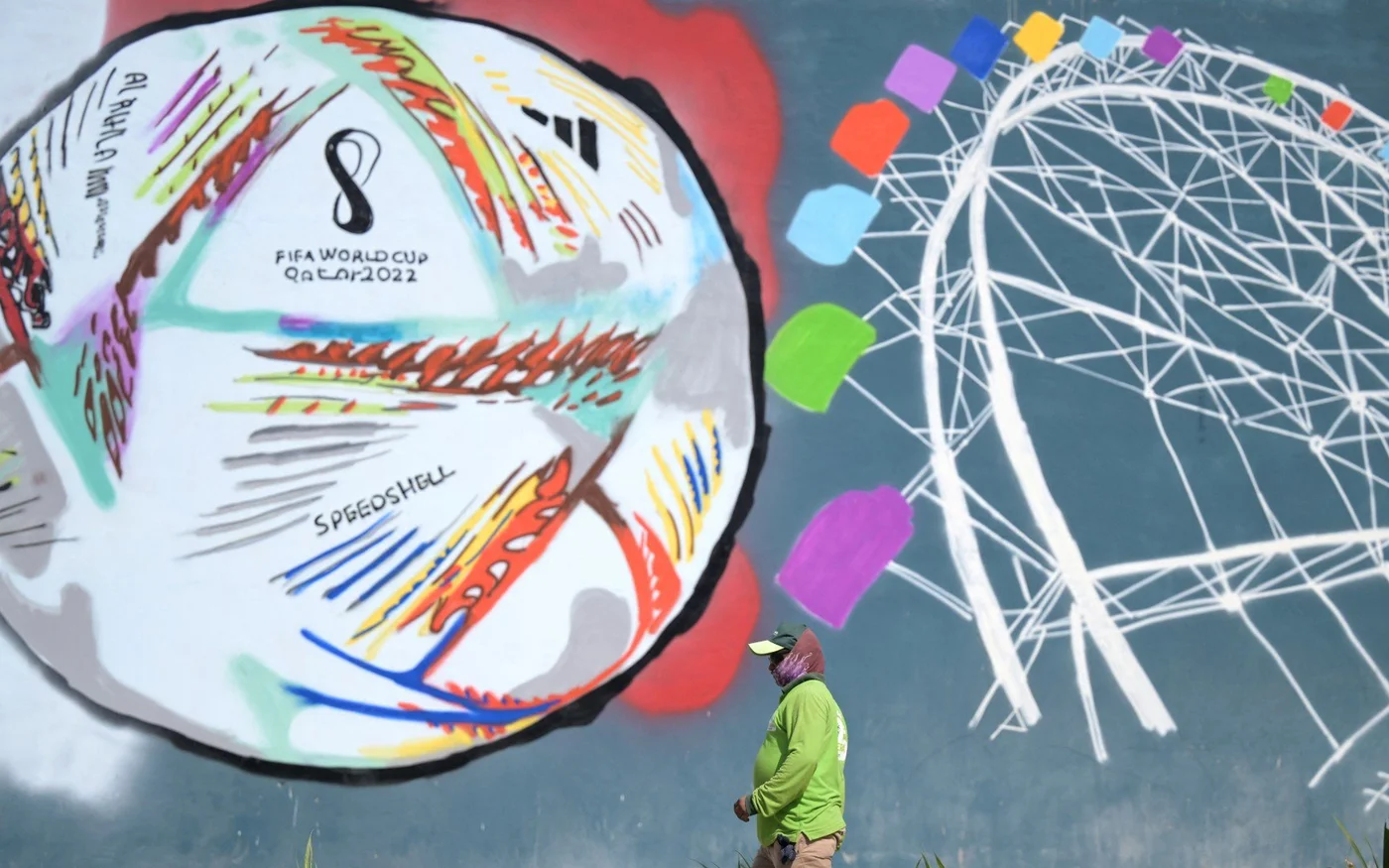 Un travailleur passe devant un graffiti le long d’une rue de Doha avant la Coupe de monde 2022 au Qatar, le 16 novembre 2022 (AFP)