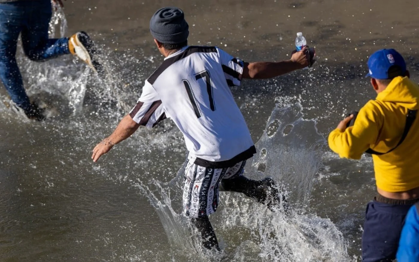 Des gens traversent le Rio Grande en courant pour rejoindre le Texas depuis le Mexique, le 8 janvier 2023 (AFP)